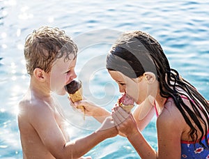 Sibling sharing ice cream by the pool photo