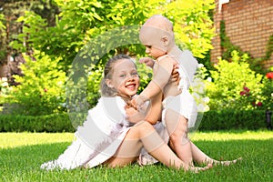 Siblings with angel wings playing on green grass