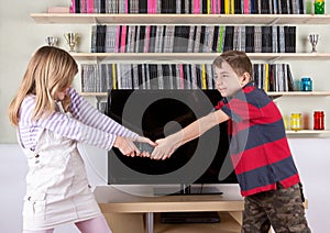 Siblings arguing over the remote control in the living room in f