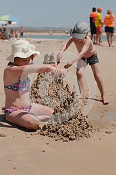 Siblings on a beach building a castles