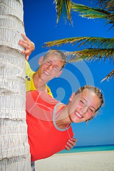 Siblings behind palm tree