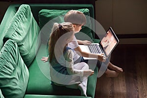 Siblings boy and girl watching kid cartoons using laptop togethe