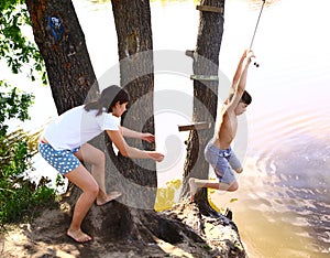 Siblings brother and sister entertain themselfs with water swing on vacation photo