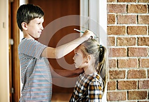 Siblings checking height home together