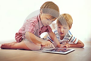 Siblings, children and tablet on a floor with cartoon, gaming or streaming movie at home. Digital, learning and boy kids