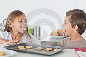 Siblings with cookies in their mouth