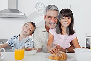 Siblings eating breakfast in kitchen together with dad