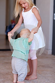 Siblings, girl and love of toddler, dancing and holding hands to play in home with happiness. House, child and growth of