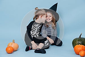 Siblings in halloween costumes touching heads and laughing.