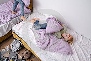 siblings having fun, laughing, boy and girl play pillow fight in messy childrens room, kids playing among the many toys