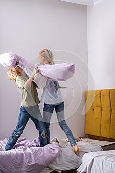 siblings having fun, laughing, boy and girl play pillow fight in messy childrens room, kids playing among the many toys