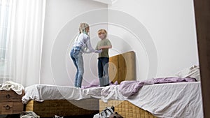 siblings having fun, laughing, boy and girl play pillow fight in messy childrens room, kids playing among the many toys