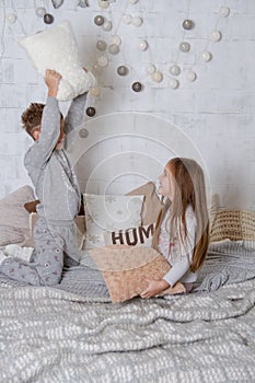 Siblings having pillow fight together on bed