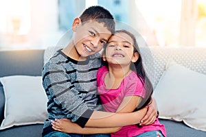 Siblings, hug and portrait of kids in home on sofa to relax with care or support of happy family. Girl, brother or