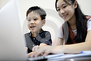 Siblings Kid boy and child girl are enjoying playing online game on laptop computer,asian sister,little brother having fun
