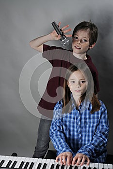 Siblings making music the girl plays keyboard and the boy sings a song