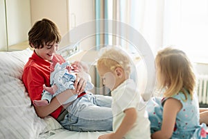 Siblings meet newborn baby in hospital photo