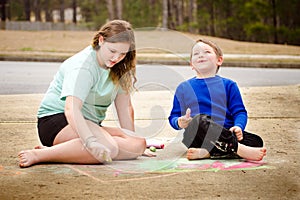 Siblings play with chalk drawing