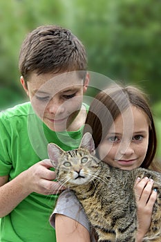 Siblings play and cuddle with their little cat