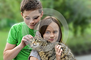 Siblings play and cuddle with their little cat