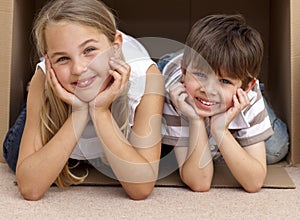 Siblings playing with boxes after moving house