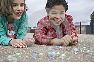 Siblings Playing Marbles On Playground