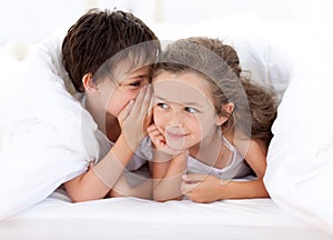 Siblings playing on parent's bed