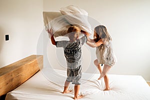 Siblings playing pillow fight on bed