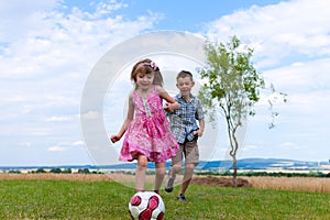 Siblings playing soccer in the garden