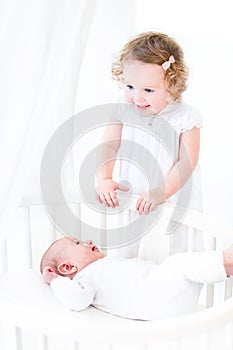 Siblings playing in sunny bedroom with round crib