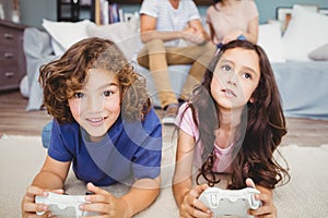 Siblings with playing video game on carpet