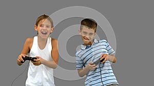 Siblings playing video games on grey screen