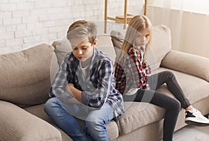 Siblings After Quarrel Sitting Back-To-Back On Couch At Home