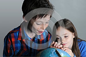 Siblings search for holiday destinations on a globe