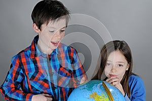 Siblings search for holiday destinations on a globe