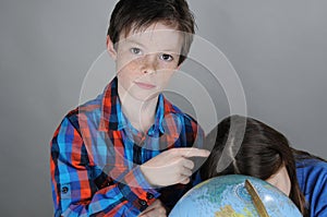 Siblings search for holiday destinations on a globe