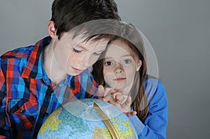 Siblings search for holiday destinations on a globe