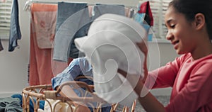 Siblings sit on the laundry room floor sorting colored clothes before putting them in the washing machine, doing