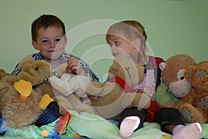 Siblings sitting in the middle of all her stuffed animals