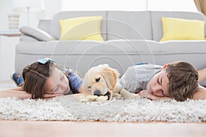 Siblings sleeping with dog on rug