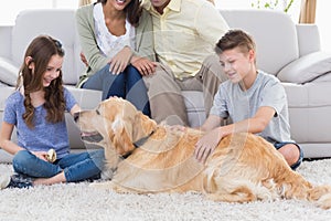 Siblings stroking dog while parents sitting on sofa