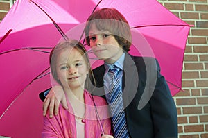 Siblings under pink umbrella