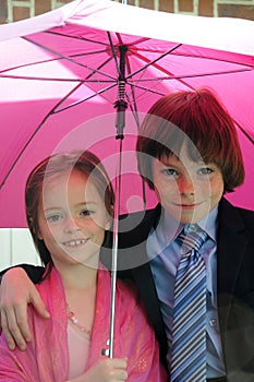 Siblings under pink umbrella