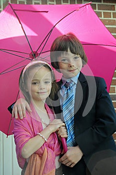 Siblings under pink umbrella