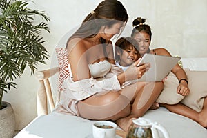 Siblings Using Tablet At Home. Portrait Of Different Age And Gender Asian Children Sitting On Sofa.