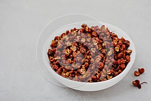 Sichuan pepper. Chinese pepper Zanthoxylum schinifolium in bowl on gray stone background