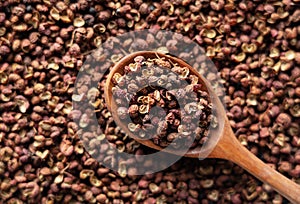 Sichuan pepper and wooden spoons placed throughout the screen
