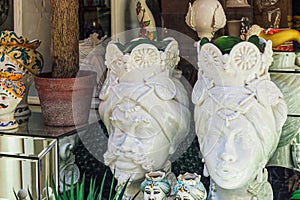 Sicilian ceramic decorative Moorish heads vases on display, depicting the faces of a man and a woman at a shop window showcase in