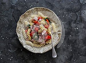 Sicilian pasta with canned tuna and cherry tomatoes on a dark background, top view