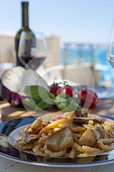 Sicilian pasta dish with traditional busiata pasta and sicilian vegetables, Viola eggplant, tomatoes served ourdoor on terrace